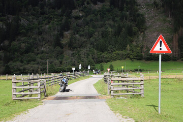 Motorrad vor dem Viehgitter, Weidergitter mit Warntafel