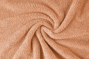 Terry cloth, orange towel texture background. Wrinkled and crumped soft fluffy textile bath or...