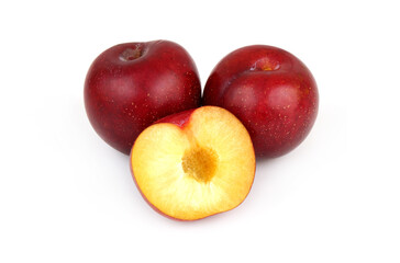 Whole and halved ripe Asian plums isolated on white background.