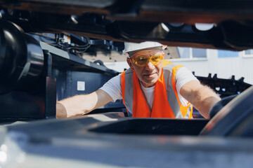 Man in hard hat, industrial worker mechanic checks hydraulic hose system equipment on excavator