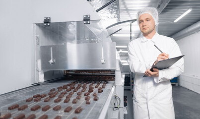 Chocolate factory man worker inspecting production line conveyor with sweets candy. Concept control...