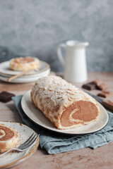Chocolate meringue roulade with almonds. Brown backdrop, blue napkin, and blue background. 
