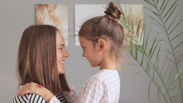 Mother embraces her daughter in the bedroom. Children bring joy and coziness to the home. Parental hugs fill the day with happiness. Affection and bonding in a cozy atmosphere.