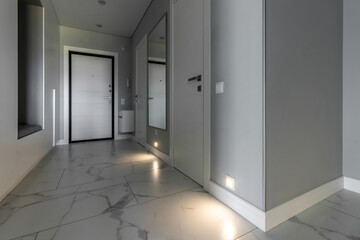 White entrance door inside the apartment in a modern interior. LED backlighting in the wall