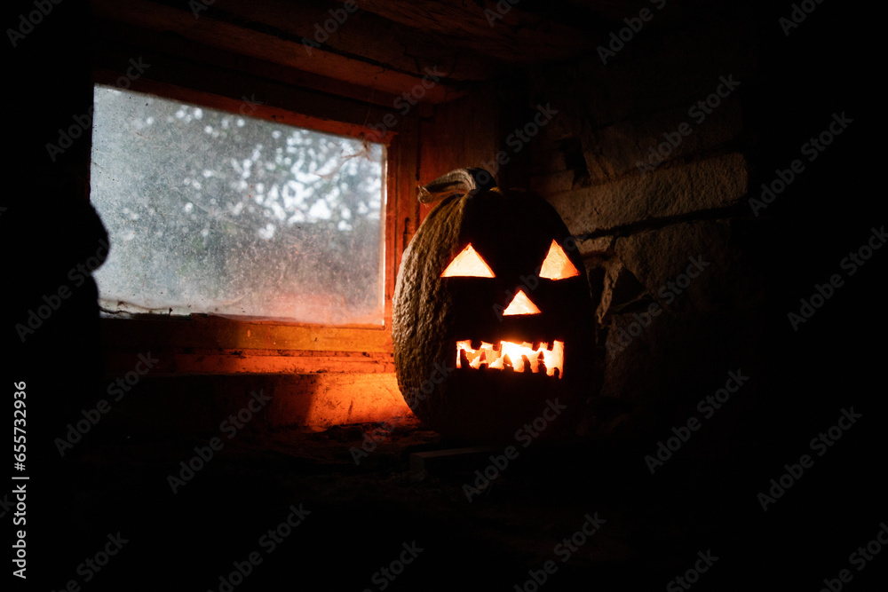 Wall mural scary Halloween pumpkin glowing in window at night