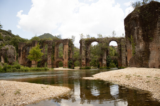 Ancient roman aqueduct with a river and plants at filipiada Greece summer natural light v2