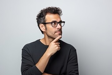 A young Caucasian man with a thoughtful expression, exuding intelligence and a hint of worry, wearing eyewear.