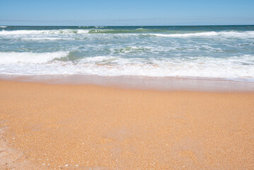 Ocean waves on a sandy beach, on a bright sunny day.