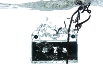 Cassette retro vintage Tape fall into clear water with air bubble. Black retro vintage cassette magnetic tape drop to wash old time. White background isolated freeze element