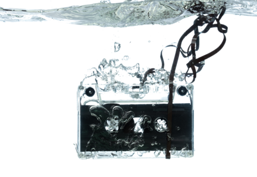 Cassette retro vintage Tape fall into clear water with air bubble. Black retro vintage cassette magnetic tape drop to wash old time. White background isolated freeze element