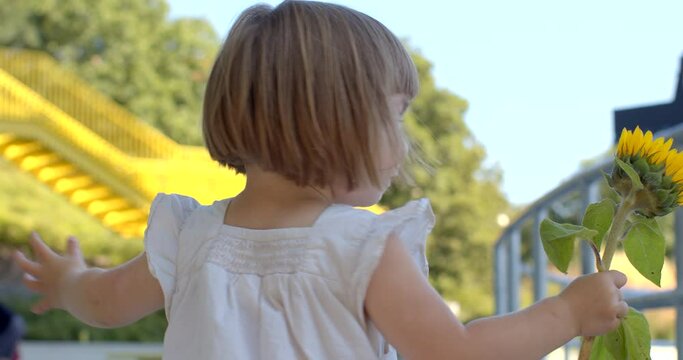 Delightful moment girl is spinning or twirling with happiness while holding a flower in her hand. Pure and carefree joy of childhood. Child with a flower radiating happiness and feelings of innocence.
