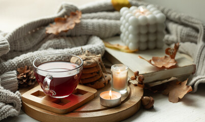 Autumn still life with a cup of tea, candles, cookies and a knitted elements. - obrazy, fototapety, plakaty