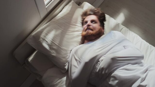 High angle time lapse of violent patient with psychosis wearing straitjacket lying on hospital bed, tossing and turning, trying to free his hands