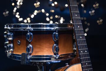 Snare drum and guitar on a blurry dark background with bokeh.