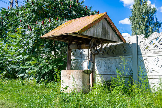 Old well with iron bucket on long forged chain for clean drinking water