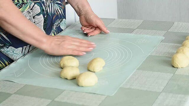 The pastry chef on the table makes balls of dough equal in weight and size with his hands to make and bake pies from them.