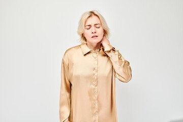 Portrait of young woman suffering from pain, touching neck isolated on white studio background....