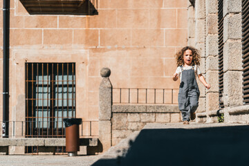 Fototapeta na wymiar little model boy running happy through world heritage streets in Cáceres