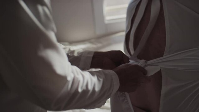 Handheld shot of mature doctor restraining violent patient with mental disorder tying up sleeves of straitjacket