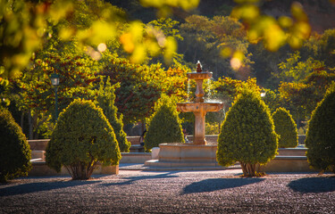 Fuente del Paseo de los Tristes - A breathtaking sunset captured through the vibrant curtain of autumn leaves, with a majestic fountain bathed in the warm, golden hues