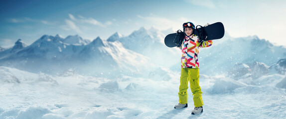 Young girl in sportswear standing with snowboard over snowy mountains background. Winter vacation....