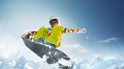Sportive girl in uniform and helmet riding snowboard over snowy mountain and blue sky background on...