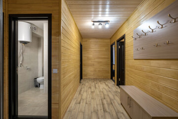 empty corridor in interior of entrance hall with many doors in wooden eco house or homestead