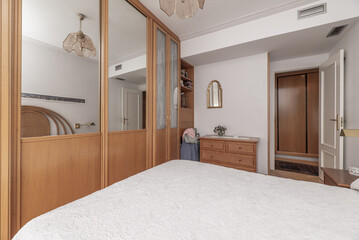 Bedroom with ducted air conditioning, furnished with a custom wardrobe with glass and mirror doors, double bed with headboard, dresser and matching nightstands
