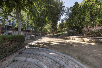 Long sandy walk with granite and stone stairs in an urban park with plenty of trees