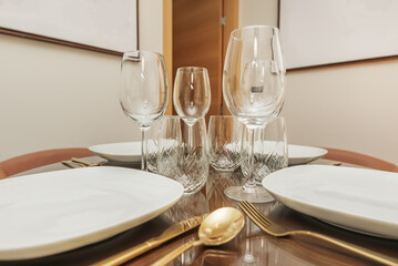 a glassware with carved goblets and glasses with a golden cutlery on a wooden table