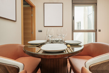 glassware with carved goblets, white porcelain plates and glasses with gold cutlery on a circular wooden table with a game foot