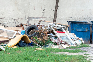 Various garbage near a blue trash can, lying on the ground