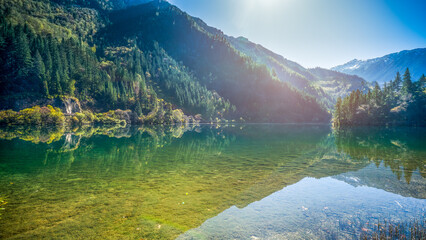 The water reflection of Arrow Bamboo Lake during noon with green yellow autumn trees , Jiuzhaigou, Sichuan, China.