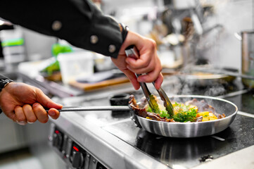 Chef cook hand cooking potato and meat food in pan at the restaurant kitchen