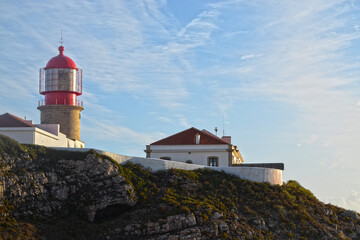 
red lighthouse with reflection of the setting sun