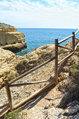 
rocky coast formed by cliffs overlooking the ocean with wooden fence in the foreground