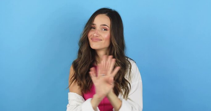 Brunette curly woman looking camera pointing fingers herself ask me no i do not need it. Girl waving her hands and say no isolated on blue background. Woman wear white shirt and pink top.