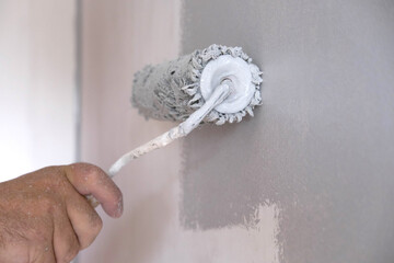 Painting walls with a paint roller. Apartment painting, renovation with gray paint