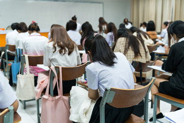 Asian college students concentrate on doing examinations in the classroom. Education stock photo