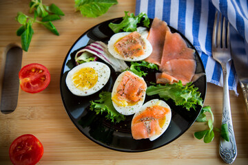 boiled eggs with salted red fish, herbs and seasonings in a plate .