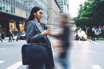 Young woman listening to music while crossing road