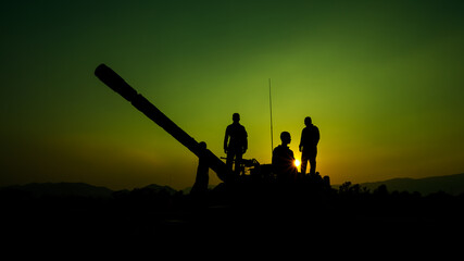 silhouette group of special forces sodiers standing and sit on tank gun truck with over the sunset...