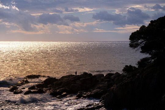 Silhouette of a man on some rocks on the coast of the Costa Brava in the province of Gerona in Spain during sunset
