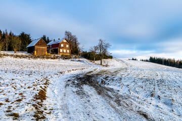 Hilly landscape with wooden rural house and first snow in early winter. Giant Mountains, Czech: Krkonose, Czechia