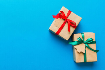 wrapped christmas or other holiday handmade present in paper with colored ribbon. Present box, decoration of gift on colourfull table, top view with copy space