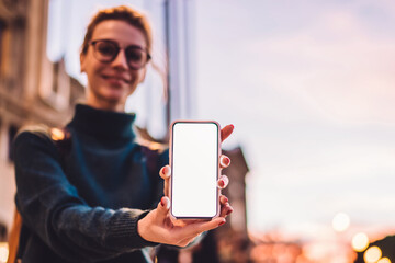 Millennial female tourist on blurred background showing modern smartphone device
