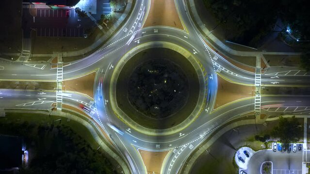 Top view of city street traffic on roundabout intersection at night with fast moving cars. Timelapse of illuminated urban circular transportation crossroads