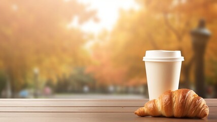 A paper cup and croissant on a wooden table with an autumn blurred background with a place for text. AI generated - obrazy, fototapety, plakaty