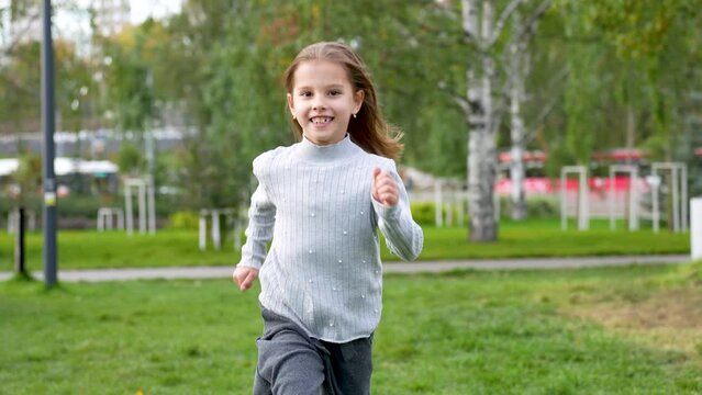 Child girl playing at playground. Cute girl running through green grass