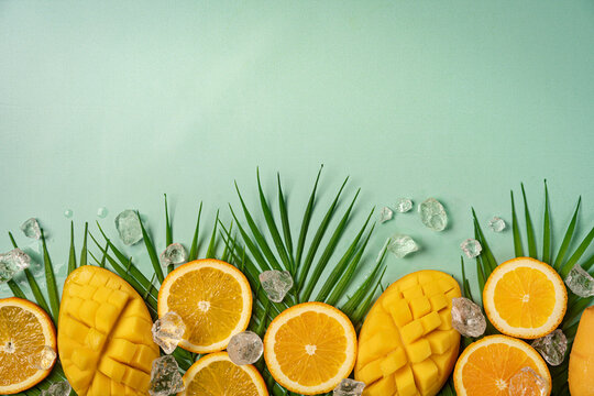 Summer colorfull concept with tropical fruits, ice and leaves on green background, flat lay, top view, copy space